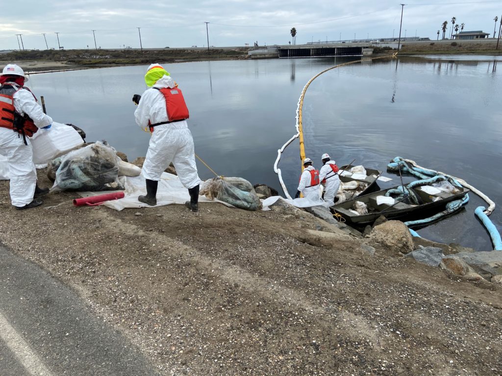 Contractors remove oil near a marsh area in Huntington Beach, California